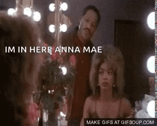 A Man And A Woman Are Standing In Front Of A Mirror . The Woman Is Looking At Herself In The Mirror . GIF
