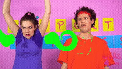 A Man And A Woman Are Standing In Front Of A Pink Wall With The Letters P And T Written On It GIF