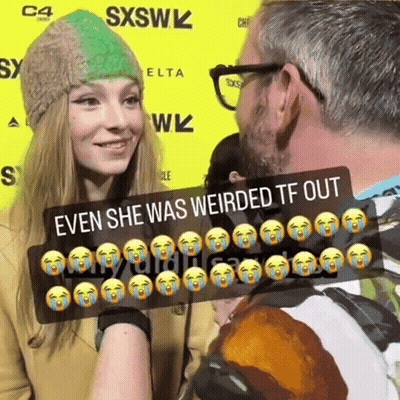 A Man And A Woman Are Standing In Front Of A Yellow Sign That Says Sxsw GIF