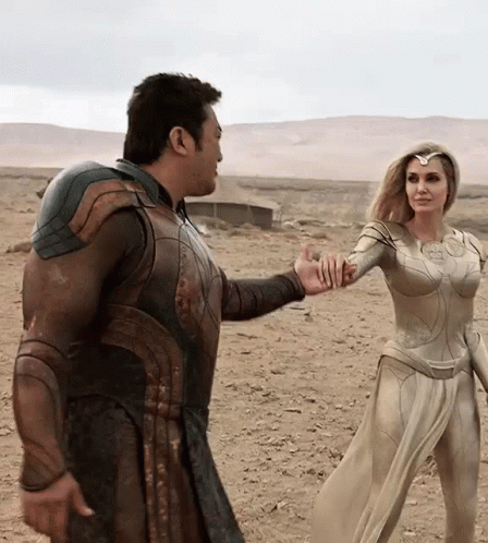 A Man And A Woman Are Standing In The Desert Holding Hands . GIF