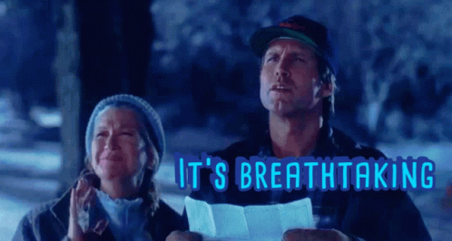 A Man And A Woman Are Standing In The Snow With The Words It 'S Breathtaking Behind Them GIF