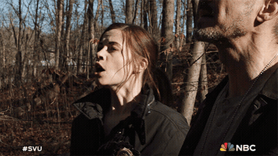 A Man And A Woman Are Standing In The Woods With A Nbc Logo On The Bottom GIF