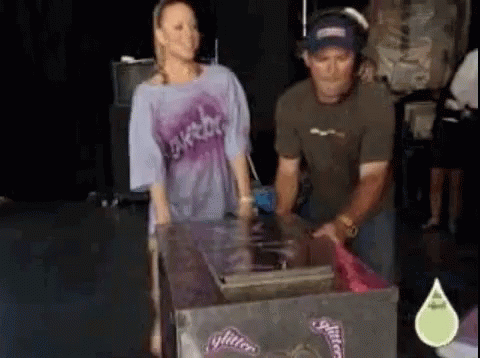 A Man And A Woman Are Standing Next To A Box That Says Glitter On It GIF