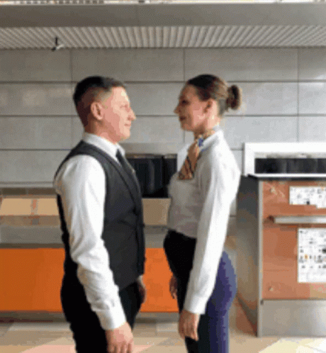 A Man And A Woman Are Standing Next To Each Other GIF