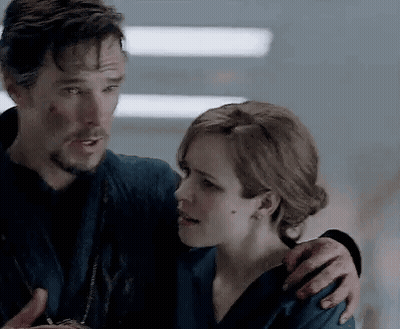 A Man And A Woman Are Standing Next To Each Other And Hugging . GIF