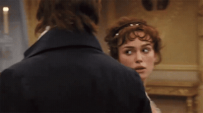 A Man And A Woman Are Standing Next To Each Other And Looking At Each Other . GIF