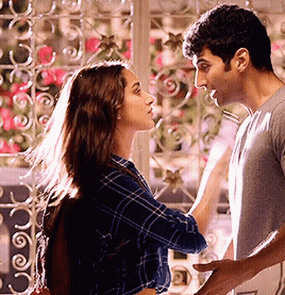 A Man And A Woman Are Standing Next To Each Other And Looking At Each Other In Front Of A Window . GIF