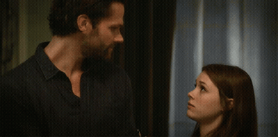 A Man And A Woman Are Standing Next To Each Other And Looking At Each Other GIF