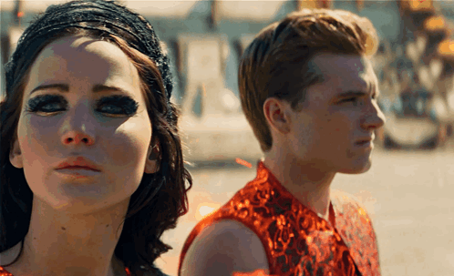 A Man And A Woman Are Standing Next To Each Other And Looking At The Camera GIF