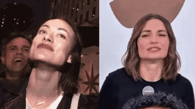 A Man And A Woman Are Standing Next To Each Other And Looking Up At The Sky . GIF