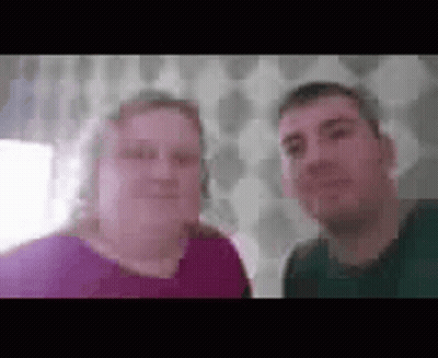 A Man And A Woman Are Standing Next To Each Other And Smiling For A Picture . GIF