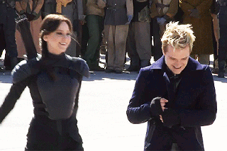 A Man And A Woman Are Standing Next To Each Other And Smiling In Front Of A Crowd GIF