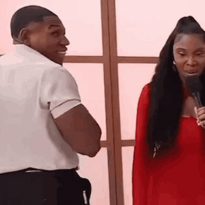 A Man And A Woman Are Standing Next To Each Other And Talking Into Microphones . GIF
