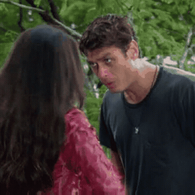 A Man And A Woman Are Standing Next To Each Other And Talking . The Woman Is Wearing A Red Dress . GIF