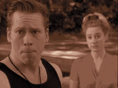 A Man And A Woman Are Standing Next To Each Other And The Man Is Making A Face GIF