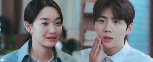 A Man And A Woman Are Standing Next To Each Other And The Man Is Touching The Woman 'S Face . GIF