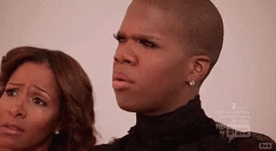 A Man And A Woman Are Standing Next To Each Other And The Man Is Wearing A Black Shirt GIF
