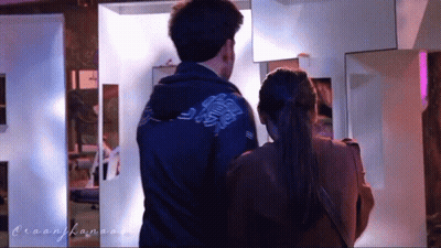 A Man And A Woman Are Standing Next To Each Other And The Man Is Wearing A Blue Jacket GIF