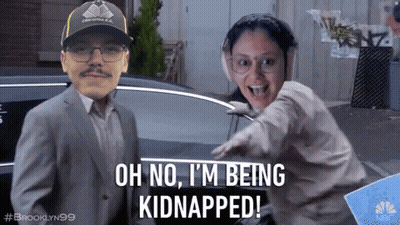 A Man And A Woman Are Standing Next To Each Other And The Man Is Wearing A Hat That Says Brooklyn 99 GIF