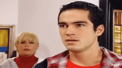 A Man And A Woman Are Standing Next To Each Other And The Man Is Wearing A Red Shirt GIF