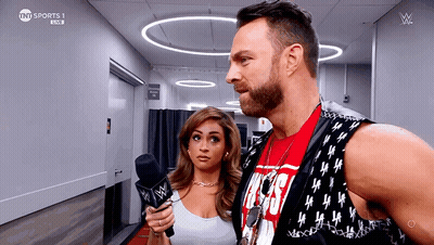 A Man And A Woman Are Standing Next To Each Other And The Man Is Wearing A Vest That Says Tnt Sports GIF