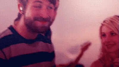 A Man And A Woman Are Standing Next To Each Other And The Man Is Wearing Headphones GIF