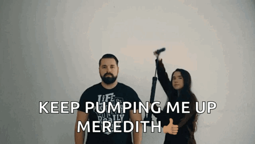 A Man And A Woman Are Standing Next To Each Other And The Woman Is Giving A Thumbs Up Sign GIF