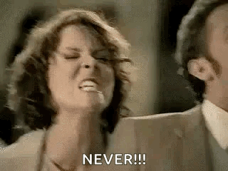 A Man And A Woman Are Standing Next To Each Other And The Woman Is Making A Funny Face And Saying `` Never '' . GIF