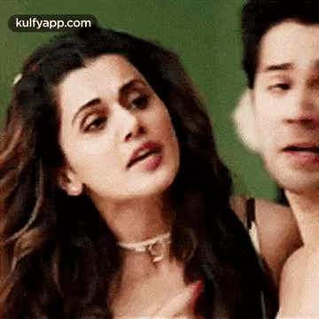 A Man And A Woman Are Standing Next To Each Other And The Woman Is Making A Funny Face . GIF