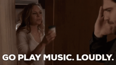 A Man And A Woman Are Standing Next To Each Other And The Woman Is Saying `` Go Play Music Loudly '' GIF