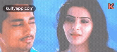 A Man And A Woman Are Standing Next To Each Other And The Woman Is Smiling . GIF
