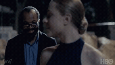 A Man And A Woman Are Standing Next To Each Other And The Woman Is Smiling While The Man Looks On . GIF