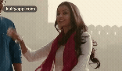 A Man And A Woman Are Standing Next To Each Other And The Woman Is Smiling . GIF