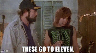 A Man And A Woman Are Standing Next To Each Other And The Woman Is Wearing A Skeleton Tank Top . GIF