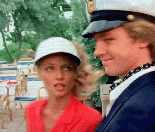 A Man And A Woman Are Standing Next To Each Other And The Woman Is Wearing A White Hat GIF