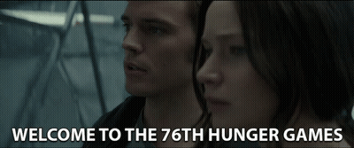 A Man And A Woman Are Standing Next To Each Other And The Words Welcome To The 76Th Hunger Games Are On The Screen GIF
