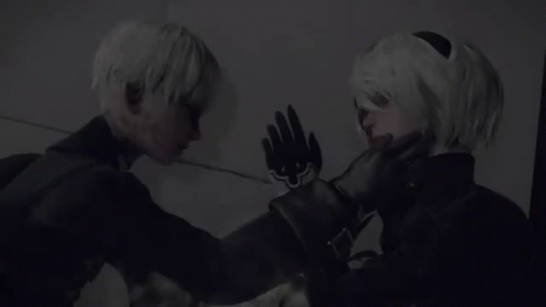 A Man And A Woman Are Standing Next To Each Other And Touching Their Faces . GIF