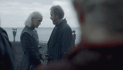 A Man And A Woman Are Standing Next To Each Other Holding Hands . GIF