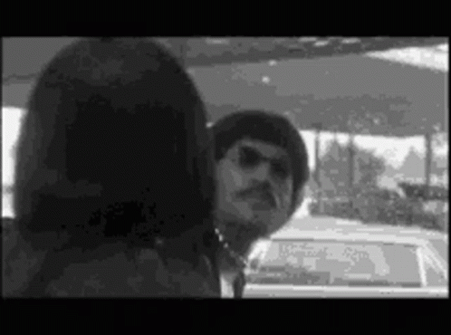 A Man And A Woman Are Standing Next To Each Other In A Car . GIF