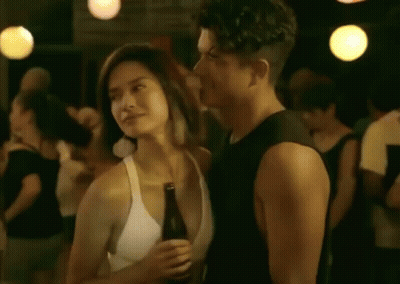 A Man And A Woman Are Standing Next To Each Other In A Crowd At A Party . GIF