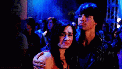 A Man And A Woman Are Standing Next To Each Other In A Crowded Room . GIF