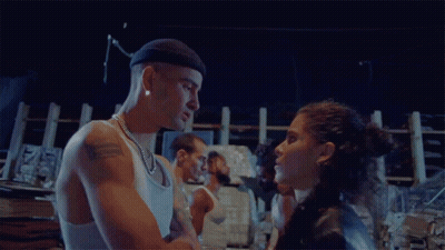 A Man And A Woman Are Standing Next To Each Other In A Dark Room GIF