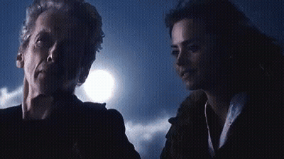 A Man And A Woman Are Standing Next To Each Other In A Dark Room With A Full Moon In The Background . GIF