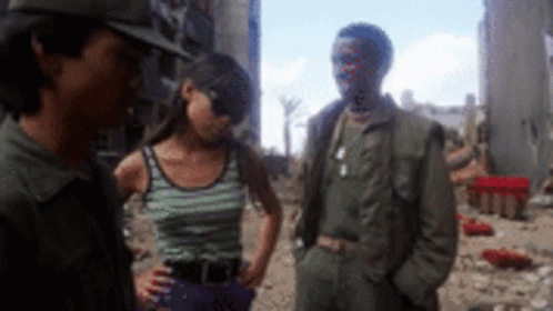 A Man And A Woman Are Standing Next To Each Other In A Field GIF