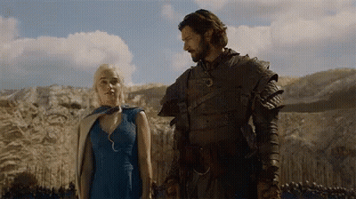 A Man And A Woman Are Standing Next To Each Other In A Field And Holding Hands . GIF