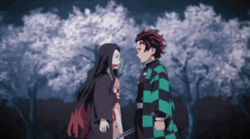 A Man And A Woman Are Standing Next To Each Other In A Forest GIF