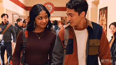 A Man And A Woman Are Standing Next To Each Other In A Hallway And Looking At Each Other . GIF