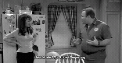 A Man And A Woman Are Standing Next To Each Other In A Kitchen . GIF