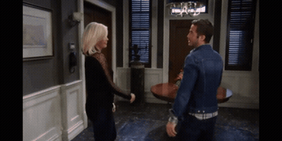 A Man And A Woman Are Standing Next To Each Other In A Living Room GIF
