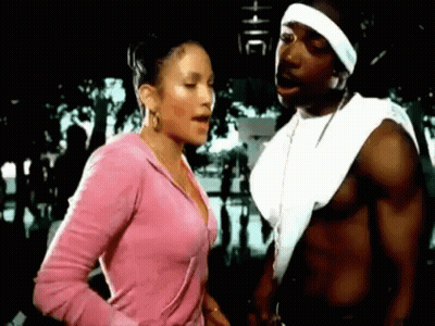 A Man And A Woman Are Standing Next To Each Other In A Park . GIF